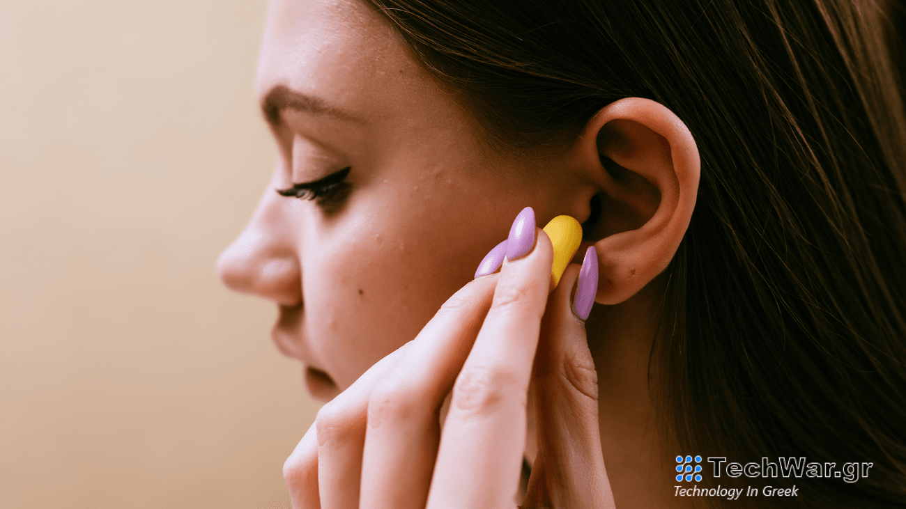 A woman puts a yellow earplug into her ear.