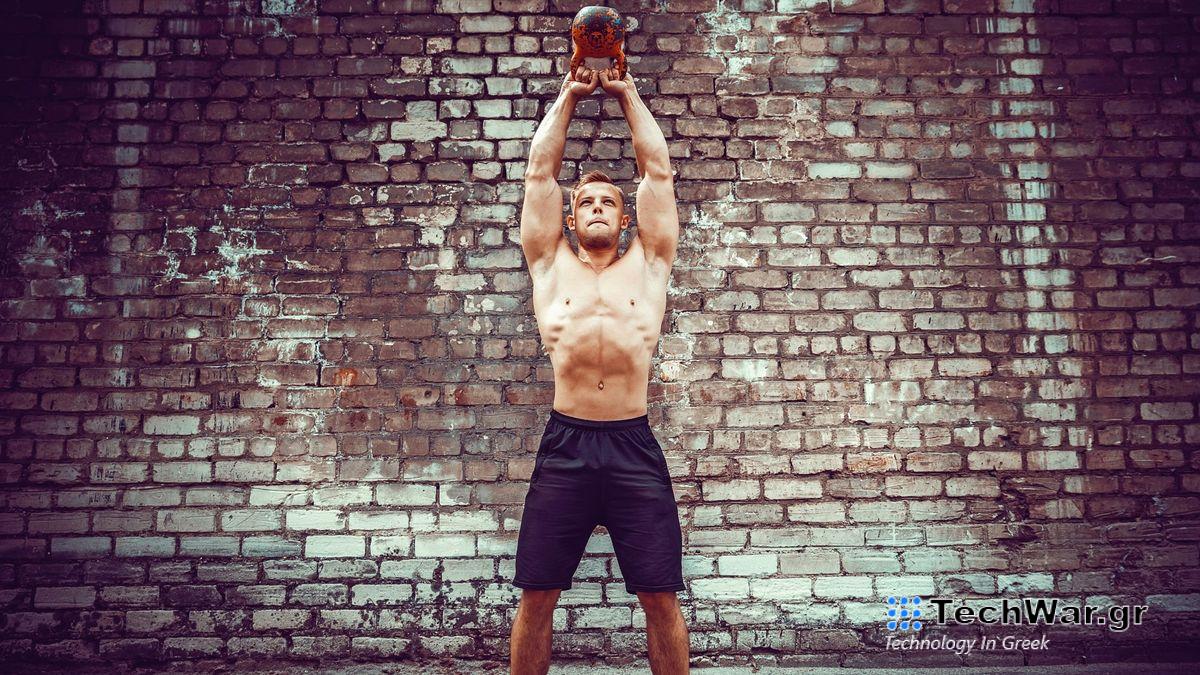 Man outside performing an American kettlebell swing against a brick wall