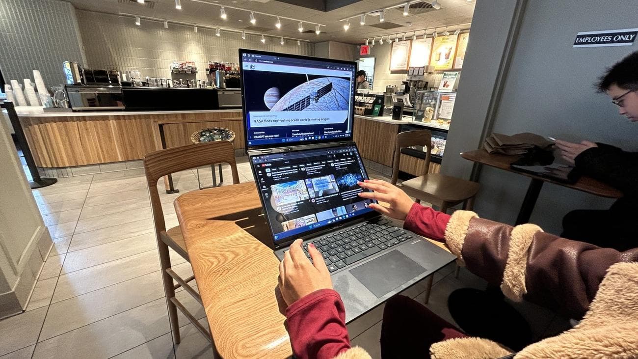Το Asus Zenbook Duo ταχυδακτυλουργεί δύο εφαρμογές με τα δάχτυλα μιας γυναίκας να αλληλεπιδρούν μαζί του