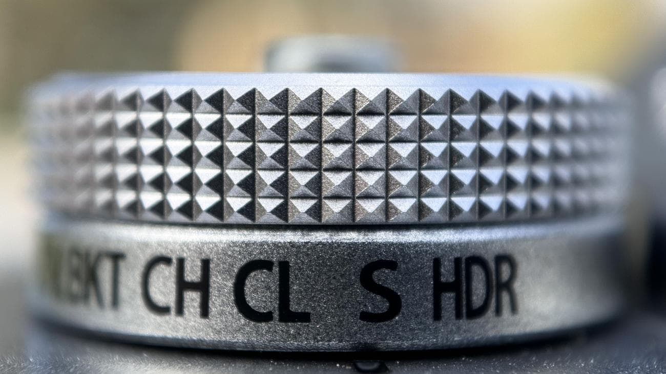 Μια κοντινή φωτογραφία ενός ασημί καντράν κάμερας που τραβήχτηκε σε ένα iPhone 15 Pro χρησιμοποιώντας τον μακρο φακό Sandmarc