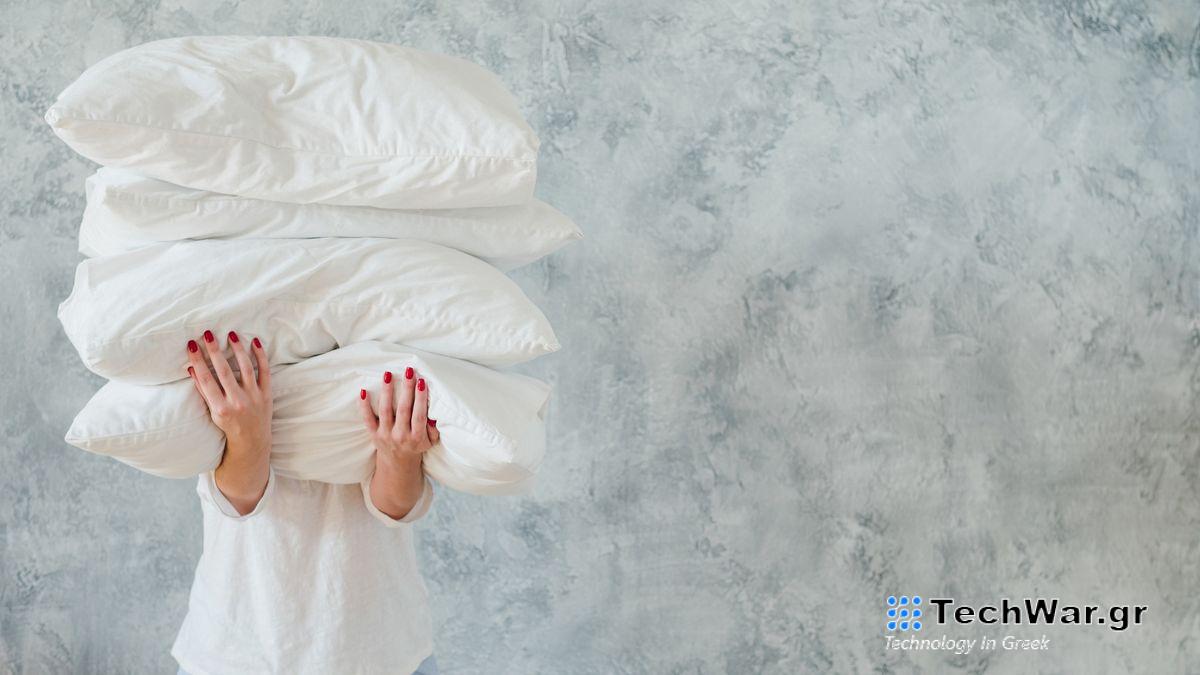 A woman with red fingernails holds a stack of clean, fluffy pillows after they have had a big spring clean