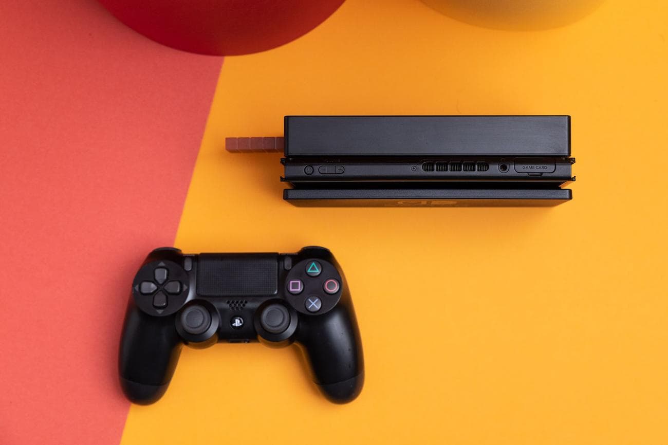 A Nintendo Switch tablet sitting inside of its dock. Next to it is Sony's DualShock 4 controller, which can be used with the Switch by way of the 8BitDo USB Adapter.