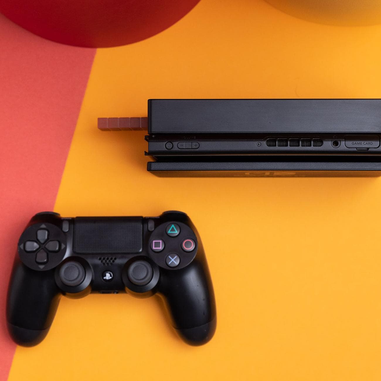 A Nintendo Switch tablet sitting inside of its dock. Next to it is Sony's DualShock 4 controller, which can be used with the Switch by way of the 8BitDo USB Adapter.