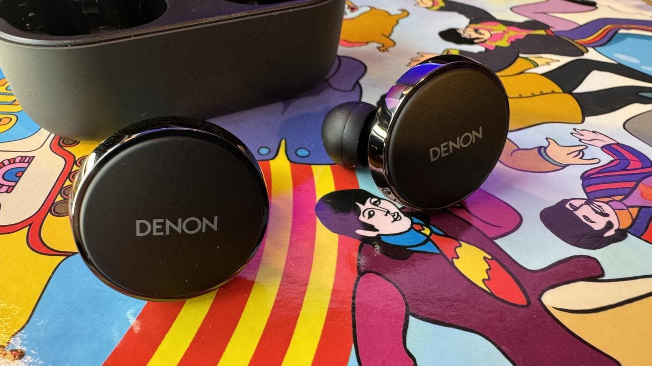Ακουστικά Denon PerL Pro σε πολύχρωμο ψυχεδελικό φόντο.