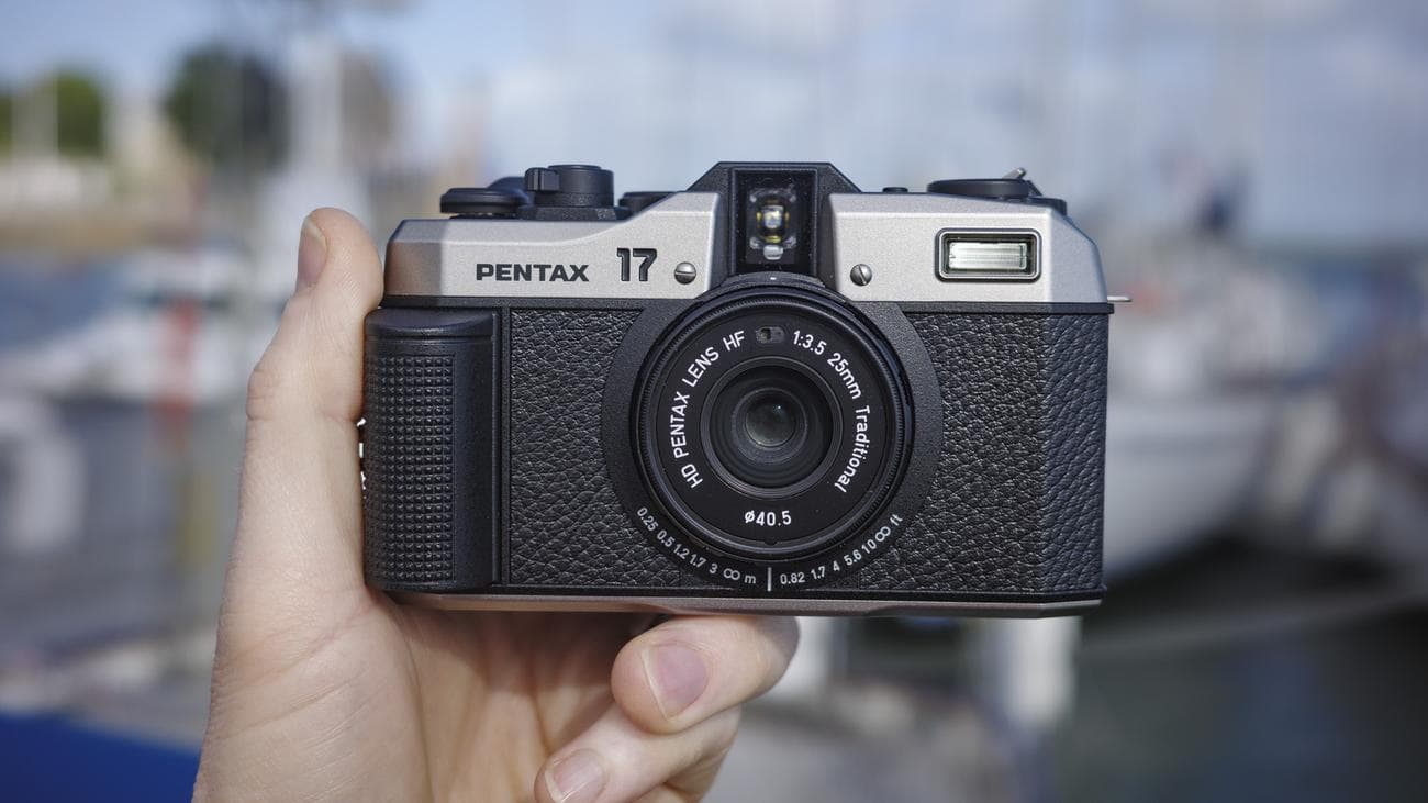 Κάμερα Pentax 17 compact φιλμ μπροστά, στο χέρι με βάρκες στο φόντο