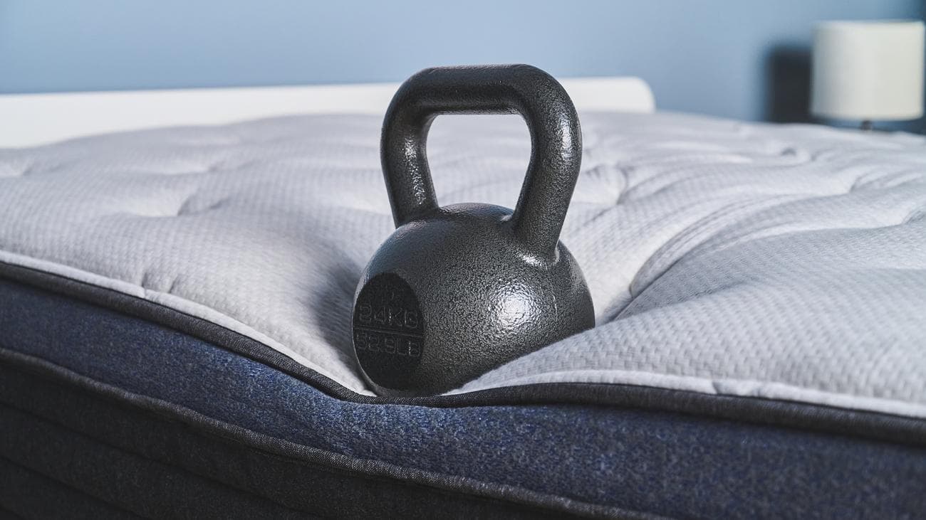 Ένα βάρος 50 lb τοποθετείται στην άκρη του στρώματος Helix Midnight Luxe για να μετρηθεί η στήριξη της άκρης