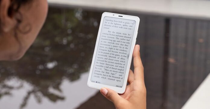 A photo of a person using a smartphone-like device near water.