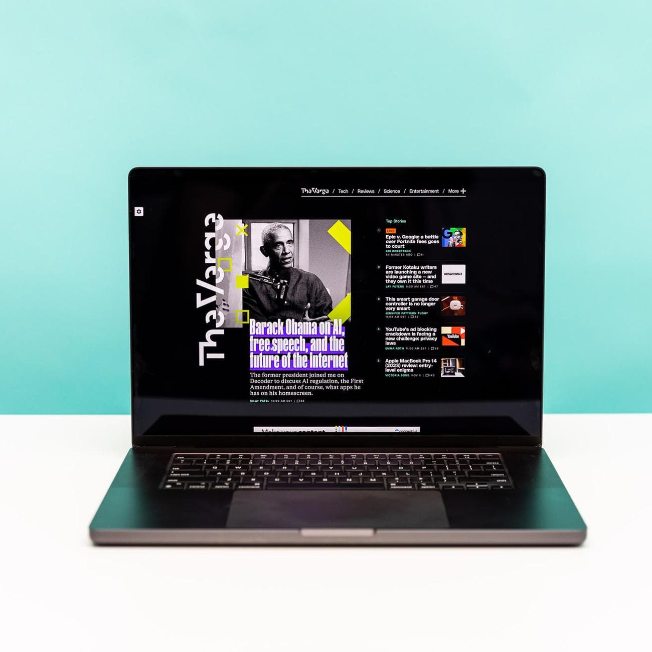 The M3 Max MacBook 16 in space black in front of a teal and white background.