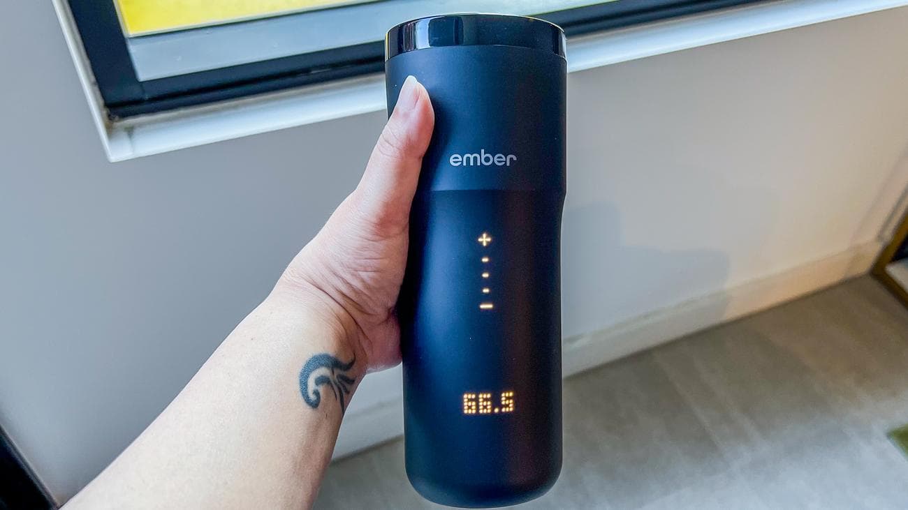 Ένα χέρι που κρατά την Ember Travel Mug 2+ με το καπάκι της οθόνης LED