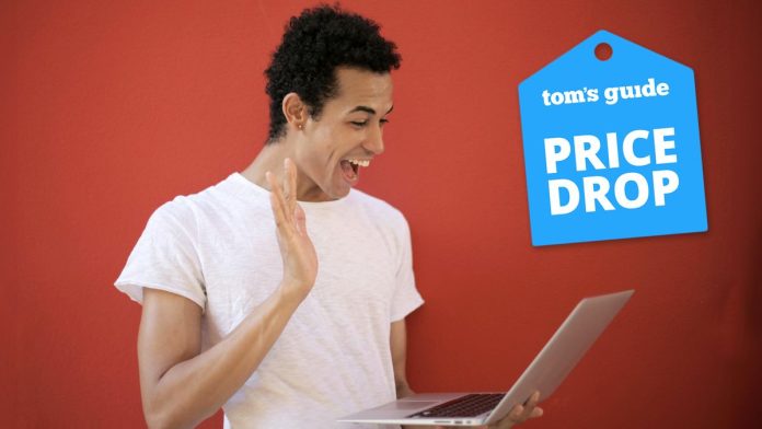 Man holding laptop and smiling, with Tom